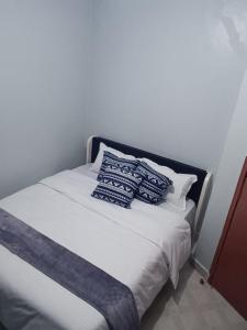 Una cama con almohadas azules y blancas. en Epic homes, Secure1 bedroom furnished partment, ample Parking and WiFi available en Nyeri