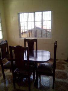 drewniany stół i krzesła w pokoju z oknem w obiekcie The Short STOP free Breakfast private Apartment w mieście Monte Plata