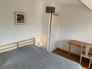 a bedroom with a bed and a table and a door at Maison village, 10 pers, proche de la plage in Audinghen