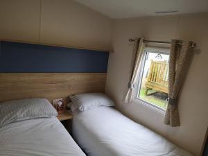 Duas camas num pequeno quarto com uma janela em Plompton Mill Holiday Home em Knaresborough