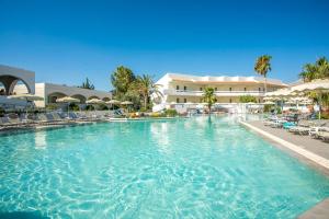 ein großer Pool mit Stühlen und ein Gebäude in der Unterkunft Hotel Niriides Beach in Kolymbia