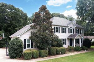 Una casa blanca con un árbol delante. en Memories by the Lake, en Gainesville