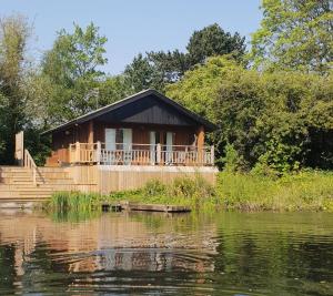 a cabin by a body of water with a house at Holly Lodge 12 Hot Tub in York