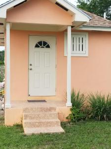 een roze huis met een witte deur en een trap bij Fishtail Palms - Sapodilly in Stuart Manor