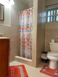 a bathroom with a shower curtain with a toilet at Fishtail Palms - Sapodilly in Stuart Manor