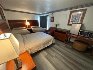 Una habitación de hotel con dos camas y un escritorio. en American Inn - Perris, en Perris