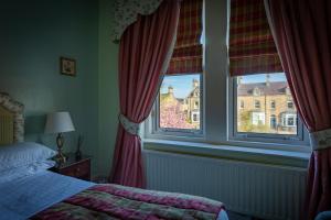 ein Schlafzimmer mit einem Bett und zwei Fenstern in der Unterkunft Homelands Guest House in Barnard Castle