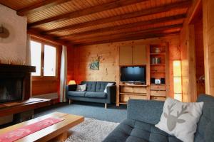 a living room with a couch and a television at Chalet Arabesque - Switzerland in Grächen