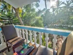 a rocking chair on a balcony with a view of a garden at Candolim Boutique House in Candolim