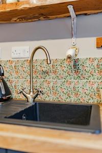 a sink in a kitchen with a floral wallpaper at The Doll's House in Holt