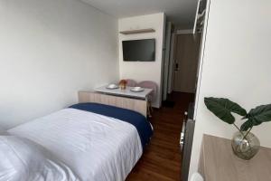 1 dormitorio con 1 cama y 1 mesa con TV en Aparta estudio acogedor 06-02, en Bogotá