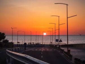 a road with a sunset on the ocean and street lights at UNIRII 107 in Constanţa