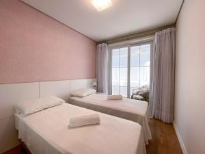 2 camas en una habitación con ventana grande en LOCAR-IN GRAMADO - Homelland no Centro de Gramado, en Gramado
