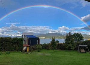 un arco iris sobre una casa con un campo verde en Private lake view cottage with BBQ yard in Paipa, en Paipa