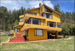 una casa amarilla con escaleras delante en Private lake view cottage with BBQ yard in Paipa, en Paipa