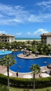 a large swimming pool with palm trees in a resort at VG Sun Cumbuco Bangalô Vista Mar in Cumbuco