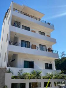 een wit appartementencomplex met een balkon bij Kavali in Los Ayala