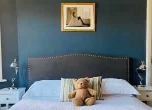 a teddy bear sitting on top of a bed at Cambridge Villa in Warwick +5 photos
