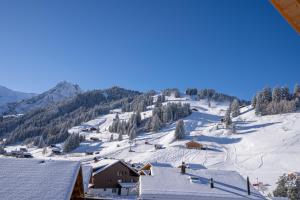 una stazione sciistica con tetti coperti da neve e una montagna di Chuenislodge3 neu&stilvoll, 2Balkone, echtes Bijou mit top-Aussicht ad Adelboden