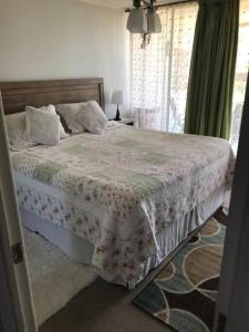 una camera da letto con un grande letto con un copriletto floreale di Hermoso DEPTO en Viña del Mar a Viña del Mar