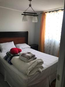 uma cama com cobertores e almofadas com uma janela em Hermoso DEPTO en Viña del Mar em Viña del Mar