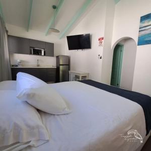 a bedroom with a white bed and a kitchen at Tropical Garden Hotel in Jacó