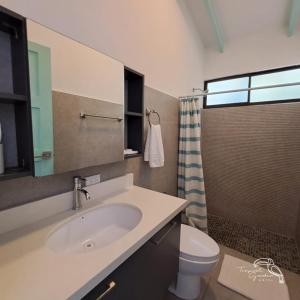 La salle de bains est pourvue d'un lavabo, de toilettes et d'une fenêtre. dans l'établissement Tropical Garden Hotel, à Jacó
