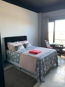 um quarto com uma cama com uma mesa e uma janela em CASA CONCEITO - studio panoramico, suites e quartos em São José