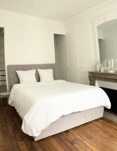 a white bedroom with a white bed and a fireplace at Arc de triomphe, Champs Elysées, Foch Avenue Luxury apartment in Paris