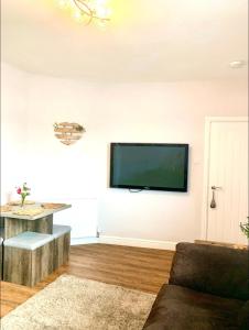 a living room with a flat screen tv on the wall at Poppy’s Place in Llandudno Junction