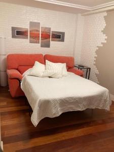 Apartamento RONDA CASTRO CENTRO con PARKING في كاسترو أورديالس: غرفة نوم مع سرير مع أريكة برتقالية