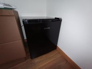 a black refrigerator in a corner of a room at Queens Leriotis Hotel in Piraeus