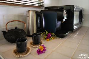 a kitchen counter with a coffee maker and some flowers at Villa Noa Noa - Matira in Bora Bora