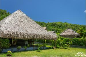 twee hutten met rieten paraplu's in het gras bij Villa Noa Noa - Matira in Bora Bora