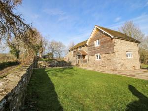 a large brick house with a stone wall and a yard at Little Bicton in Craven Arms