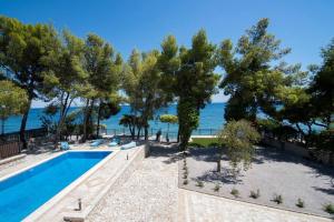 an outdoor swimming pool with trees and the water at villa lion in Agioi Theodoroi