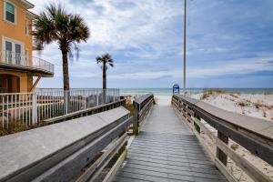 a boardwalk to the beach with a house and palm trees at Destin Townhome with Balcony - Walk to the Beach! in Destin