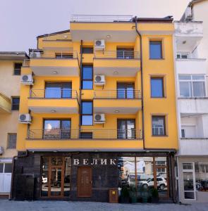 a yellow building with a balcony on a street at Guest House Velik in Sandanski