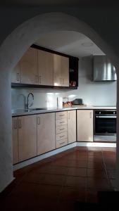 a kitchen with white cabinets and a sink and an archway at Casa cueva Bandama con jacuzzi in Tafira