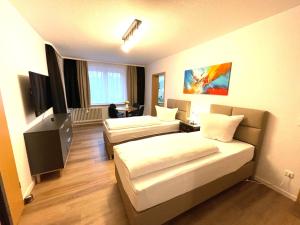 a hotel room with two beds and a television at Park-Residenz Isernhagen in Hannover