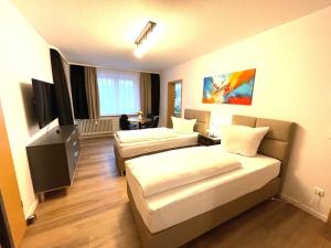 ハノーファーにあるPark-Residenz Isernhagenのベッド2台とテレビが備わるホテルルームです。