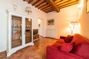ein Wohnzimmer mit einem roten Sofa und einem Fenster in der Unterkunft Podere Vergianoni con piscina e vista mozzafiato in Tavarnelle in Val di Pesa