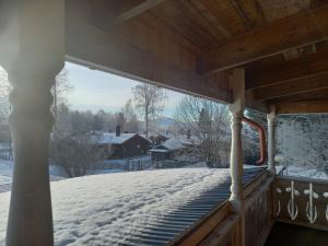 un porche cubierto de nieve con vistas a una casa en Lägenhet centrala Sollerön, en Sollerön