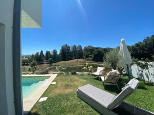 un patio trasero con piscina, sillas y sombrilla en Luxury Home - Vila Golfe Amarante, en Amarante