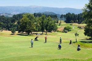 a group of people playing golf on a golf course at Moradia - Vila Golfe Amarante in Amarante