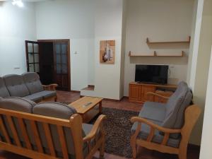 een woonkamer met een bank en stoelen en een tv bij ALBERGUE CASA LAS ANGELITAS 