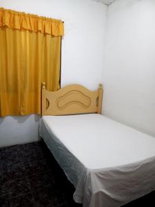 a bed in a room with a yellow curtain at RANCHO PÉ DA SERRA in Capitólio