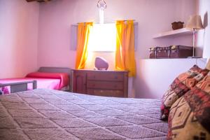 Schlafzimmer mit einem Bett und einem Fenster mit gelben Vorhängen in der Unterkunft La Nelida Posada in Chilecito