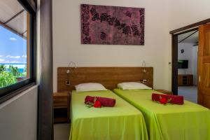 two beds in a room with green sheets and red pillows at FARE ATEA in Bora Bora