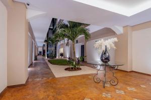 um corredor com uma mesa e palmeiras num edifício em Hotel Plaza by Kavia em Mérida